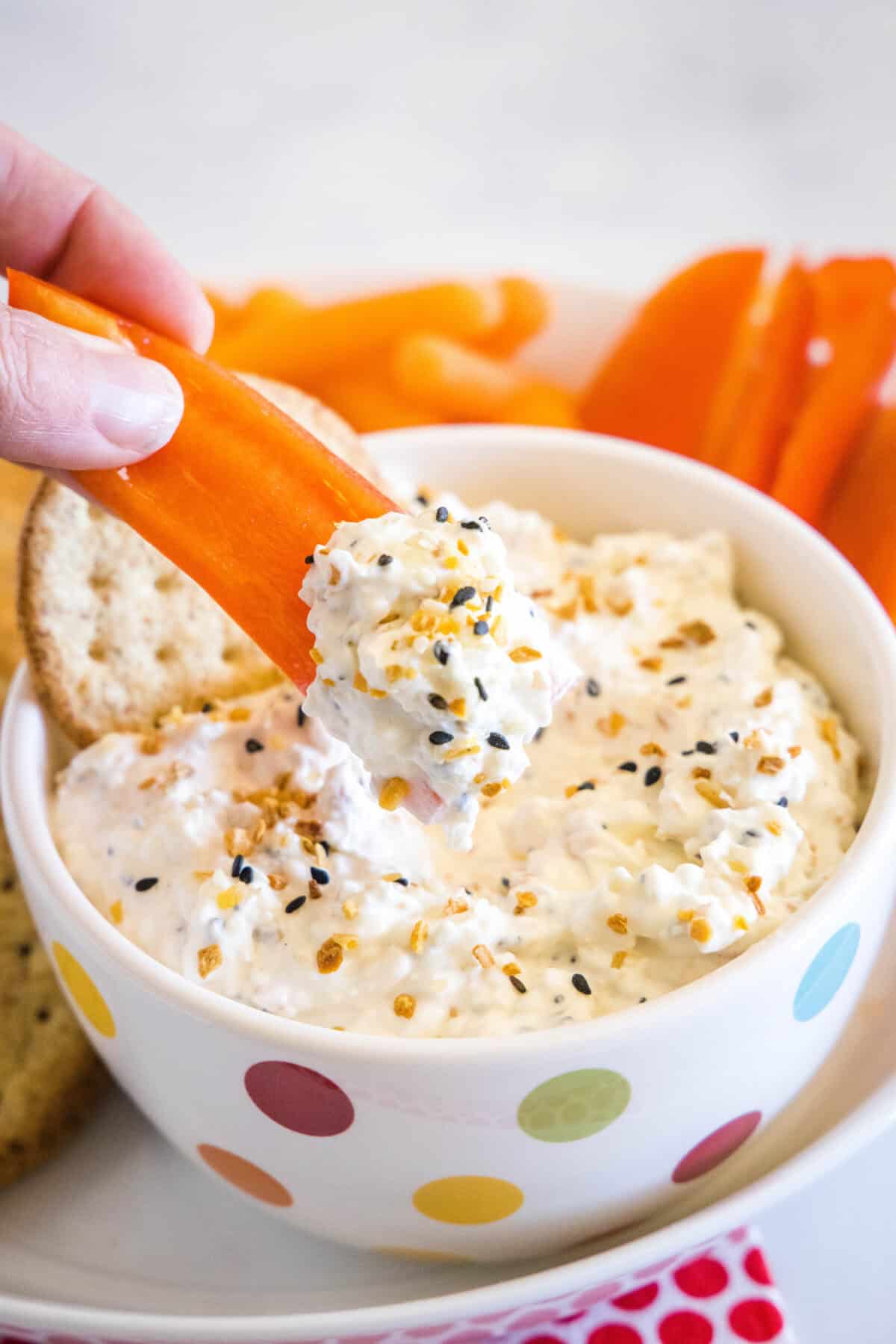 scooping everything bagel dip with a red pepper