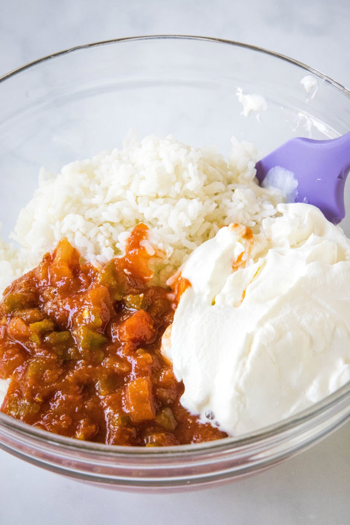 Rice, sour cream, and salsa combined in a glass bowl.