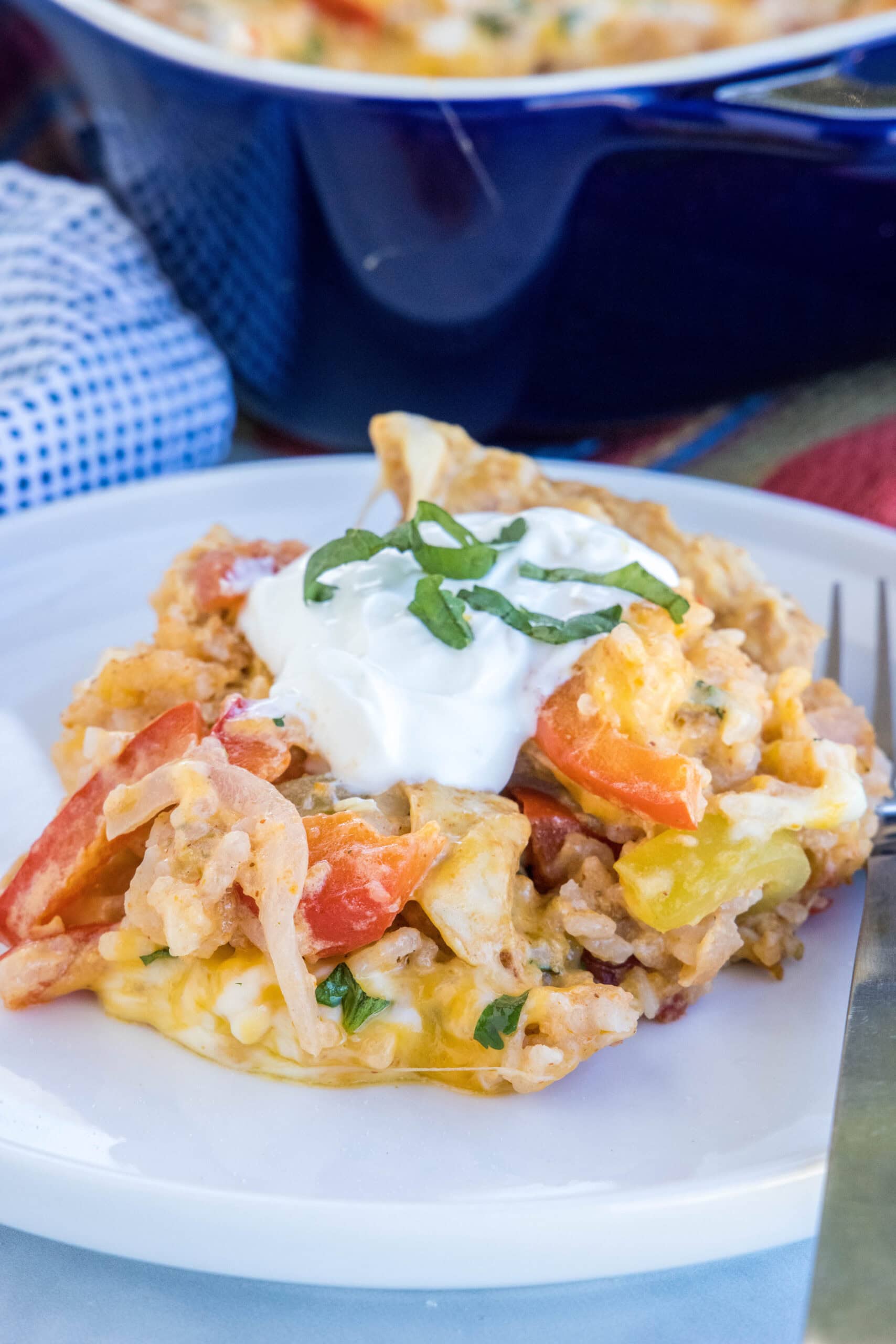 A serving of chicken fajita casserole on a white plate next to a fork.