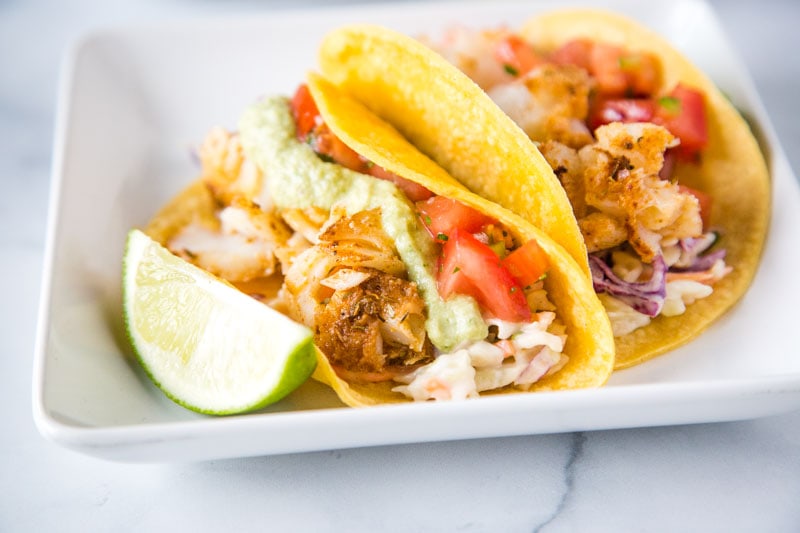 Easy Fish Tacos - a super easy, healthy, and delicious cod fish taco recipe.  Topped with a fresh Mexican coleslaw, pice de gallo, and a roasted poblano fish taco sauce. 