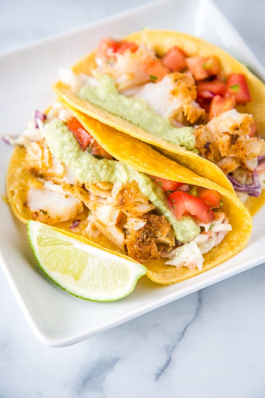 cod fish tacos with poblano cream sauce, pico de gallo and lime wedge