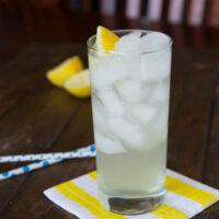 A cup of lemonade sitting on top of a wooden table, with Lemon and Lemonade