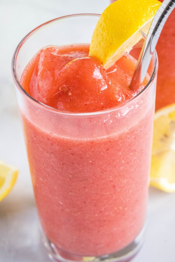 a glass of frozen strawberry lemonade for a slice of lemon