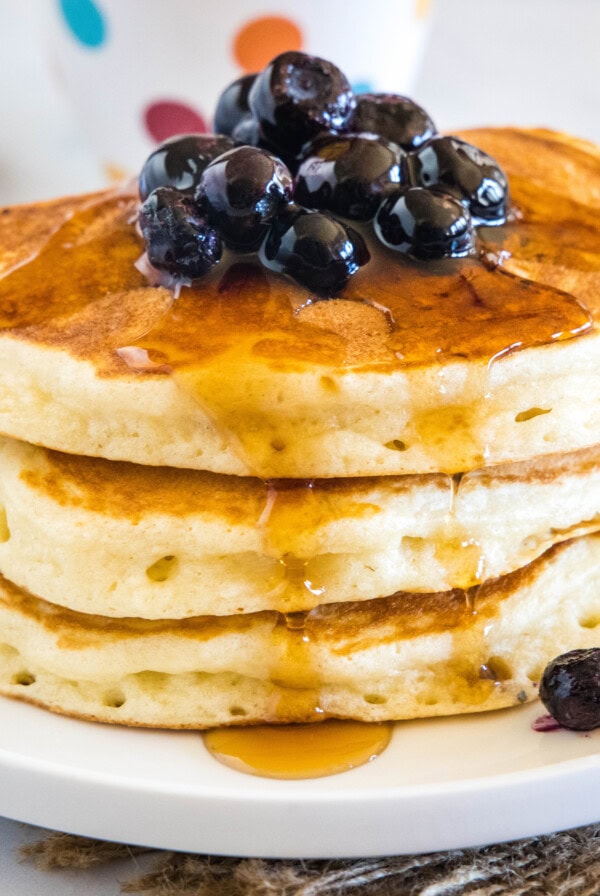 cropped close up of stack of pancakes with syrup and blueberries