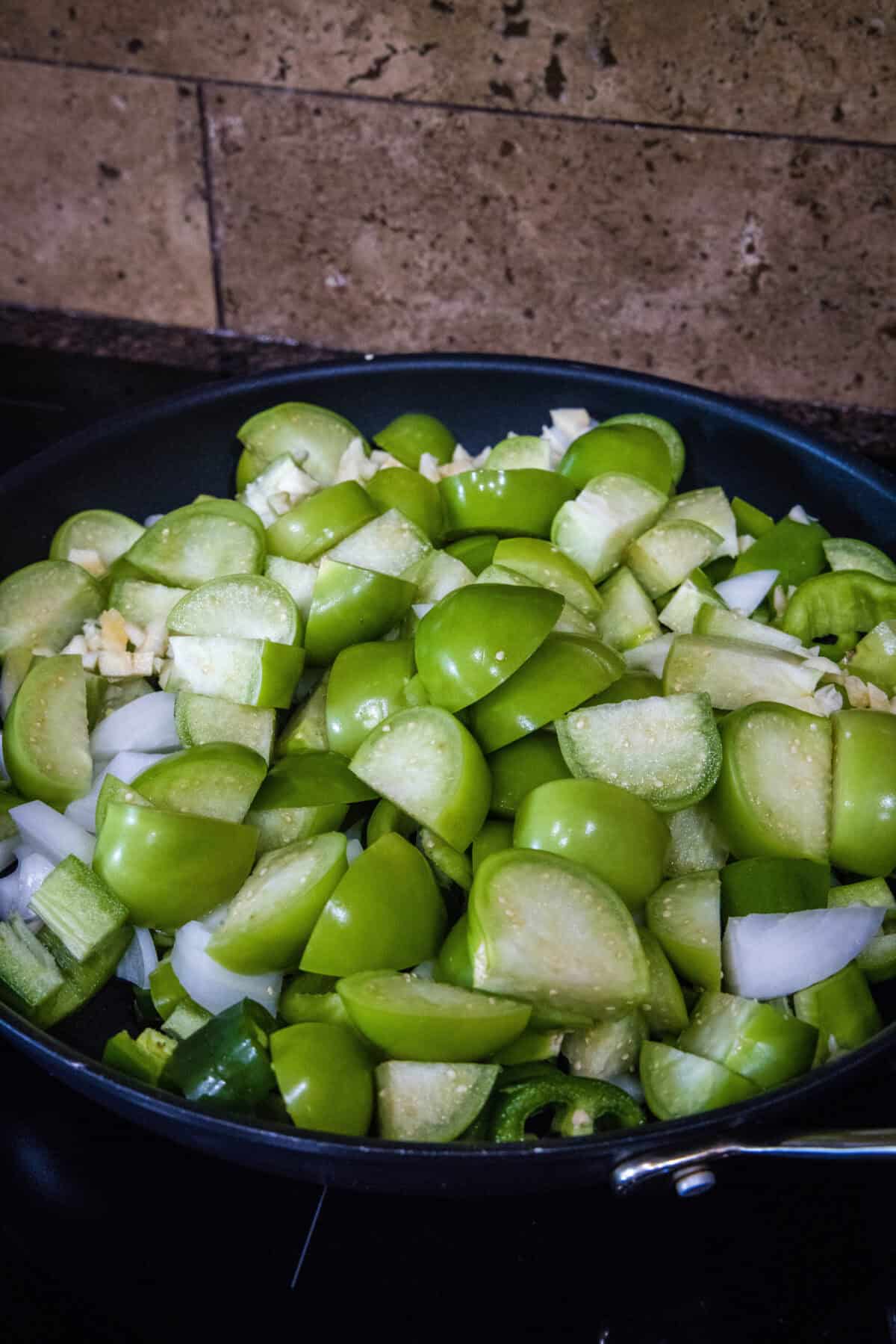 adding vegetables to a pan to cook for enchialda sauce