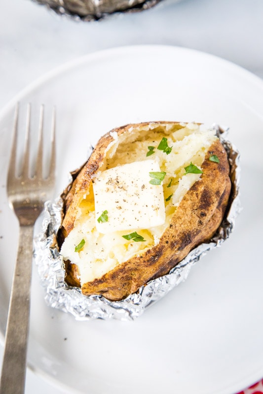 cut open baked potato with butter and chives