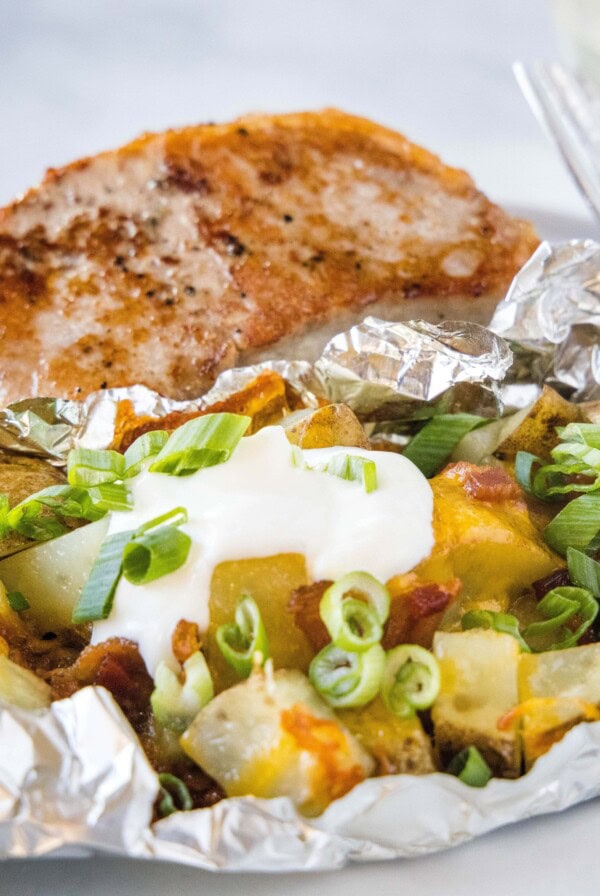 grilled potato pack on a plate with a pork chop