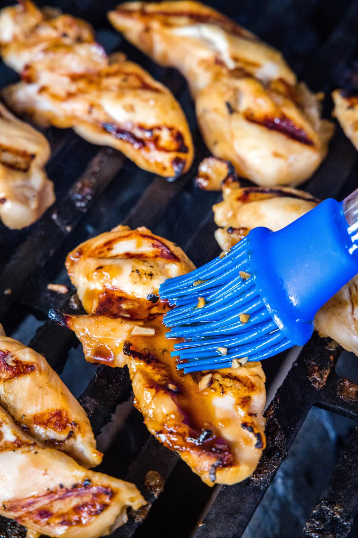 A rubber basting brush is used to baste the chicken with teriyaki sauce while it grills.
