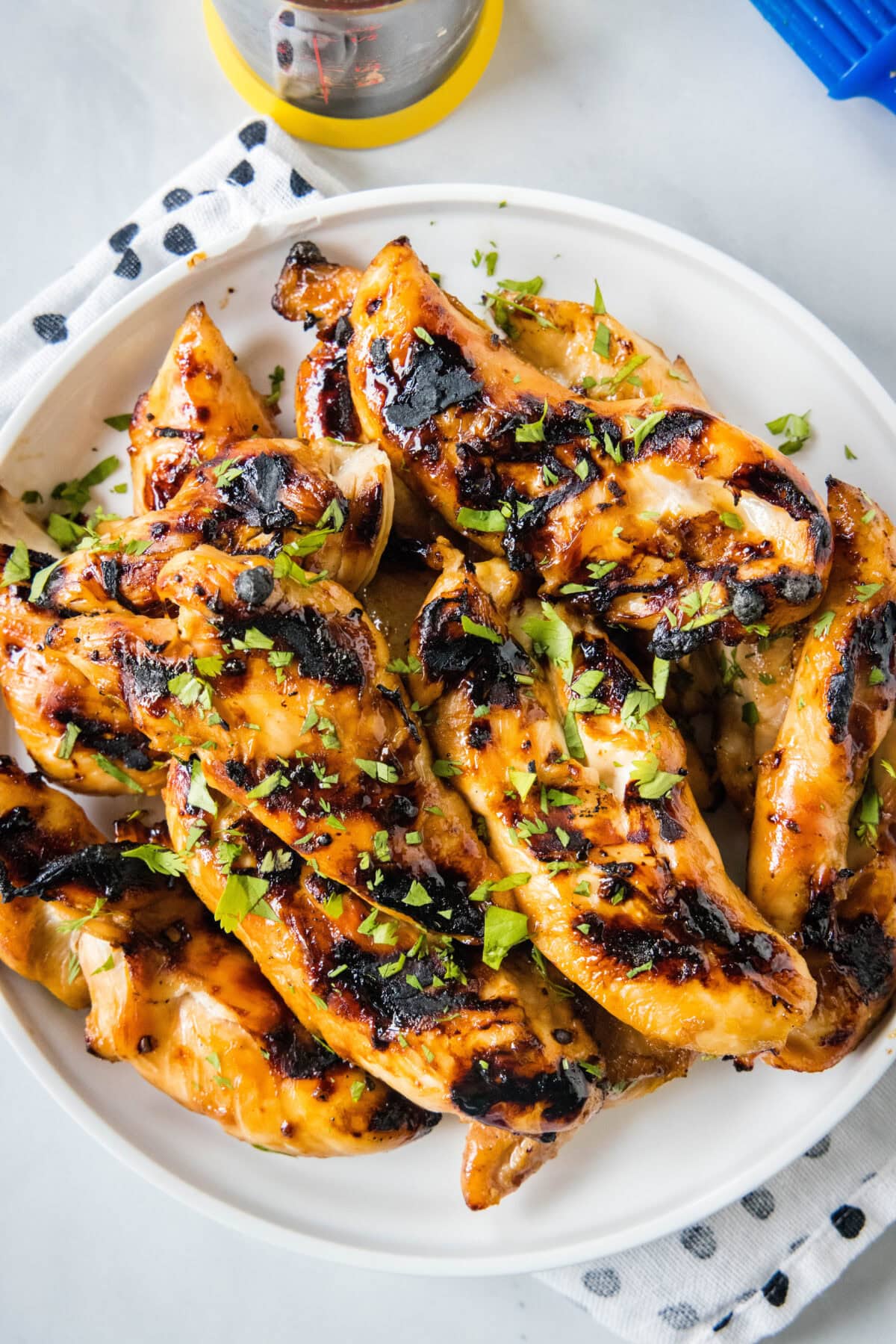 Overhead view of grilled teriyaki chicken piled on a white platter.