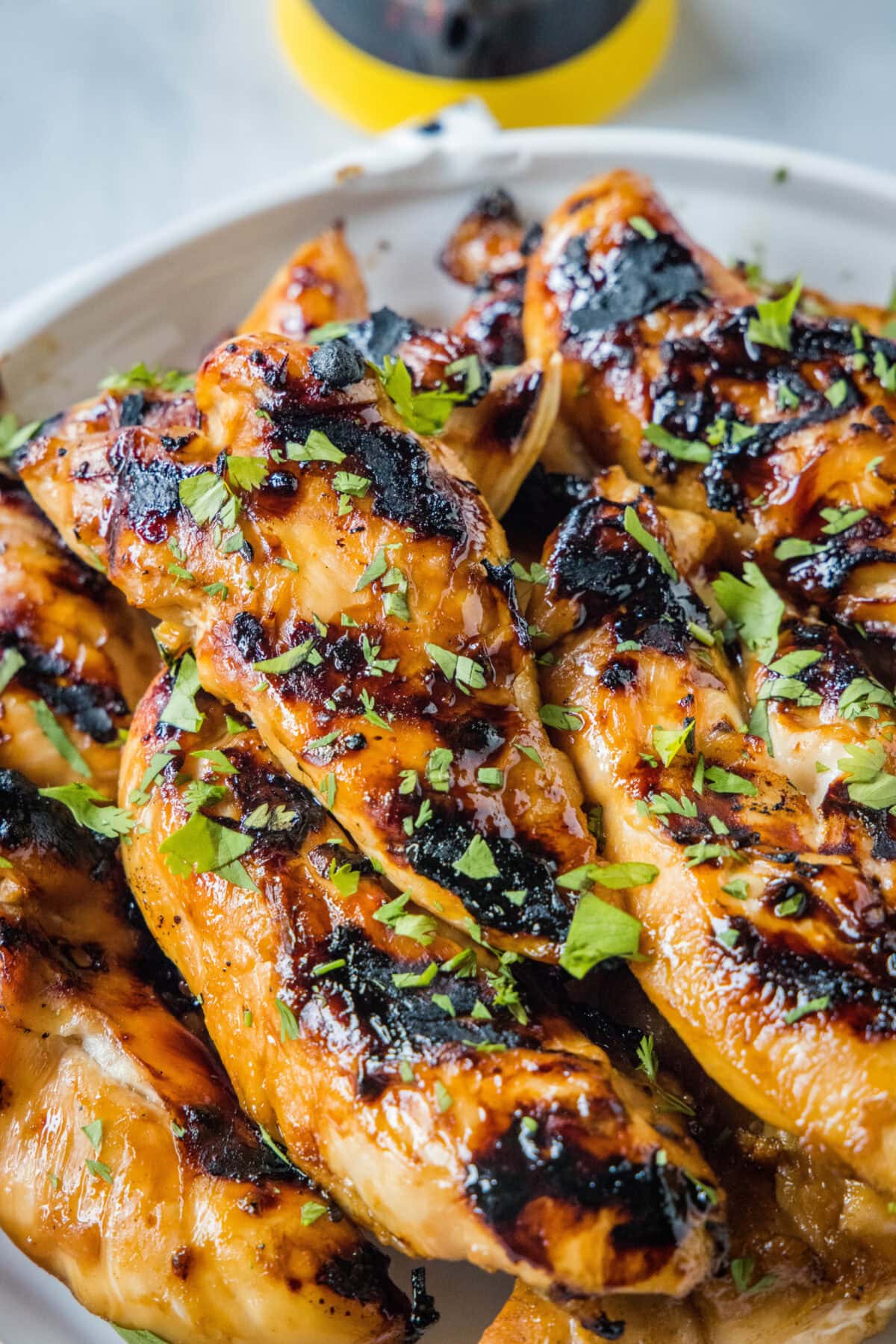Close up of teriyaki grilled chicken piled on a white platter.