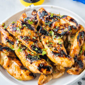 Teriyaki grilled chicken piled on a white platter.