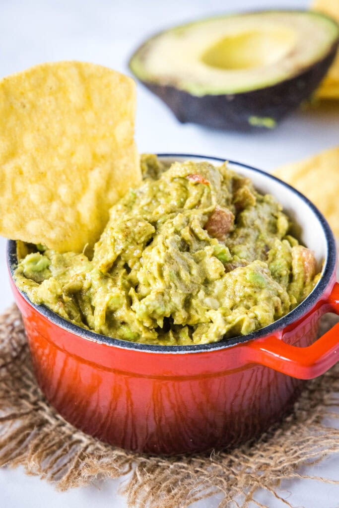 a chip dipping into a bowl of guacamoel