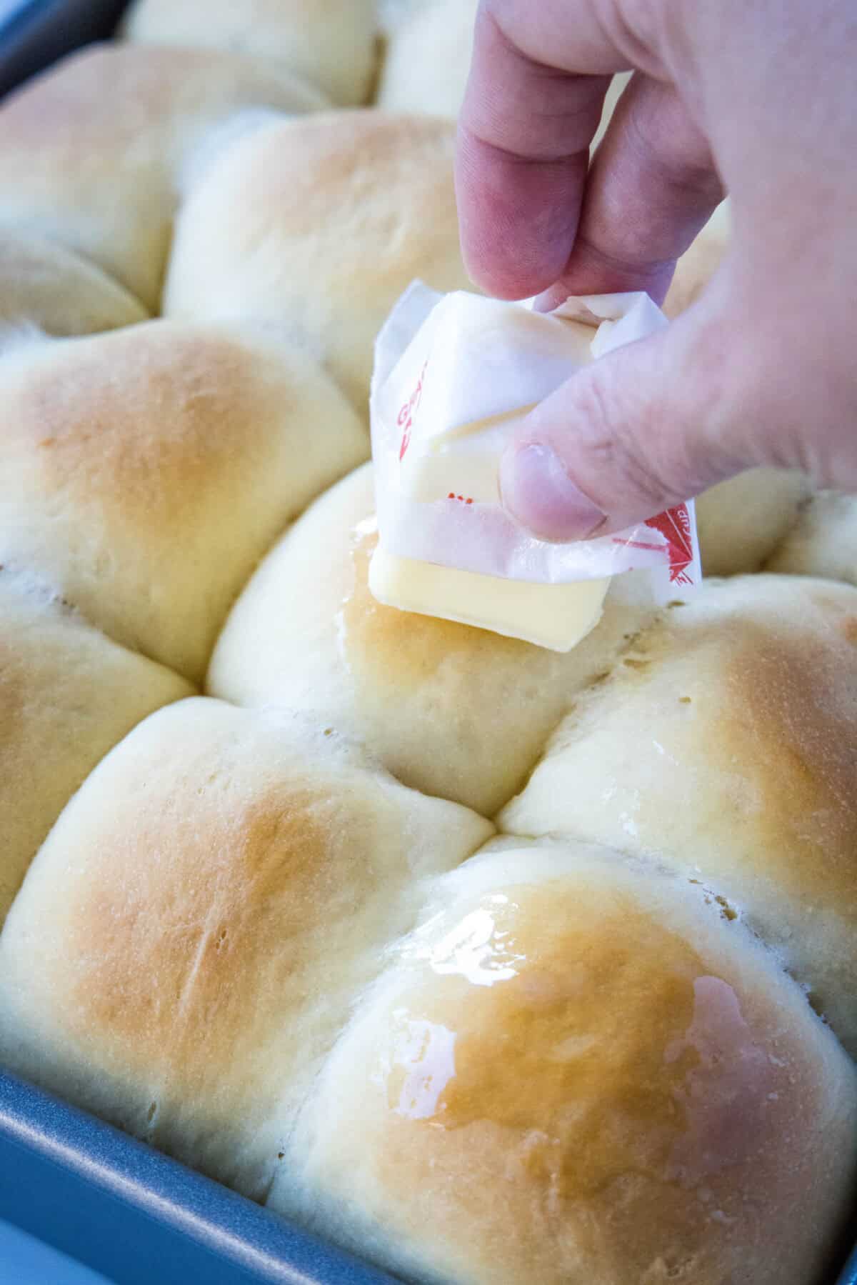 spreading butter on baked rolls