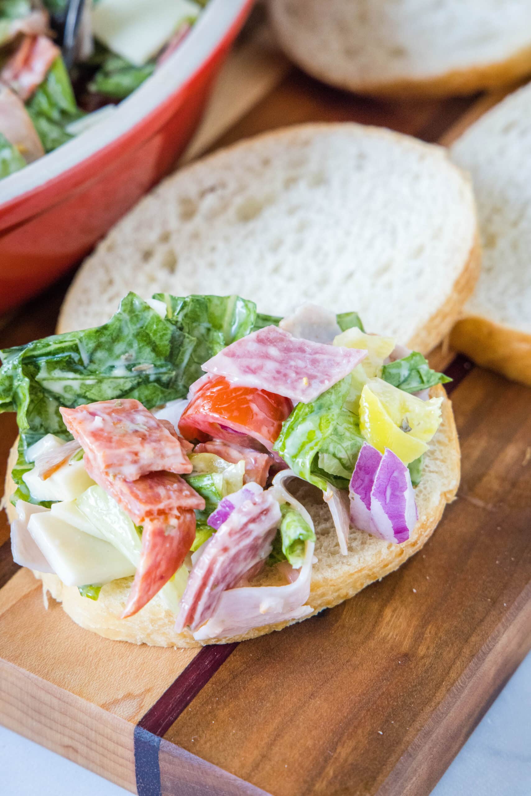 Hoagie dip piled onto a slice of bread with more bread slices and the bowl of dip in the background.