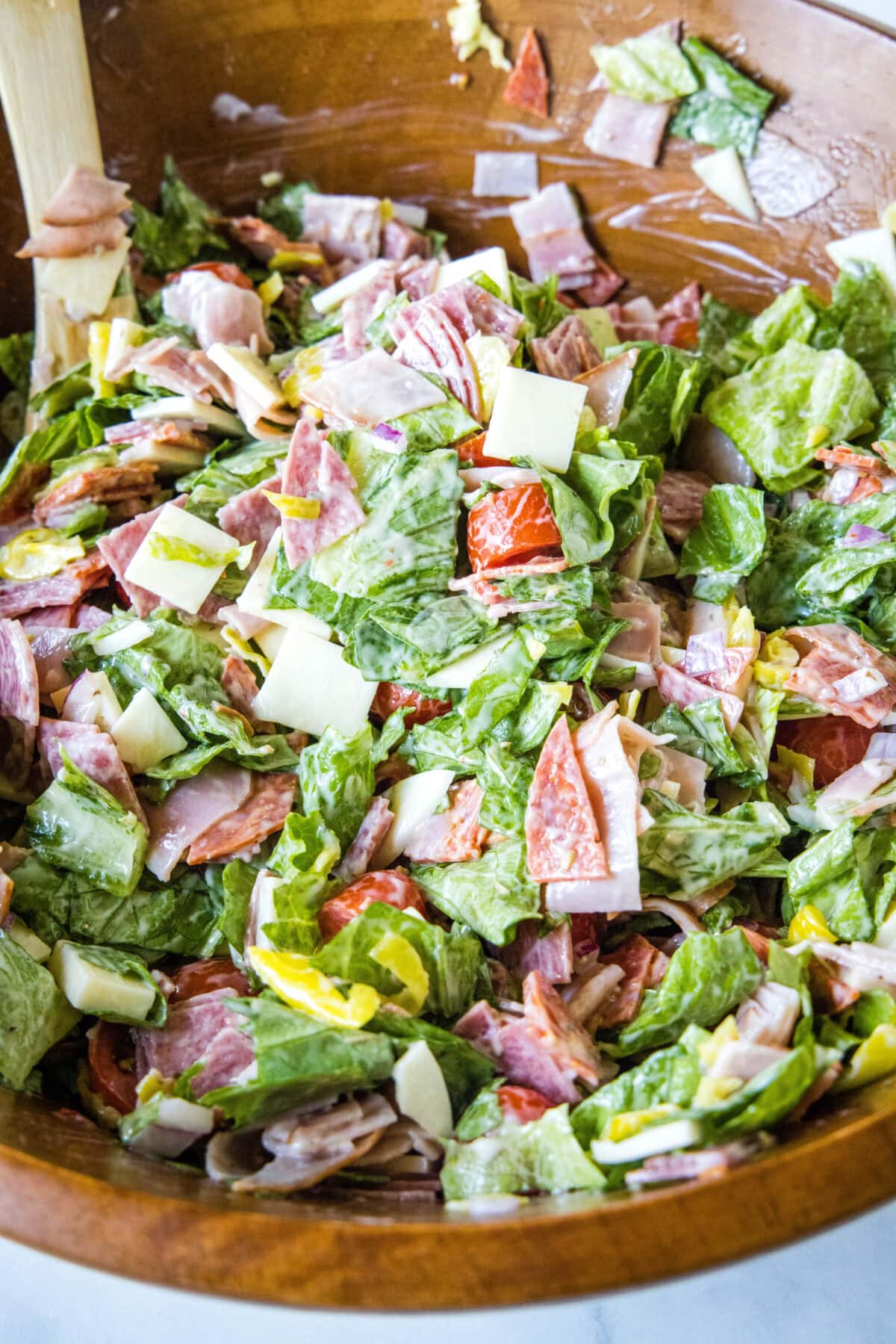 Hoagie dip tossed together in a wooden bowl with a spoon.