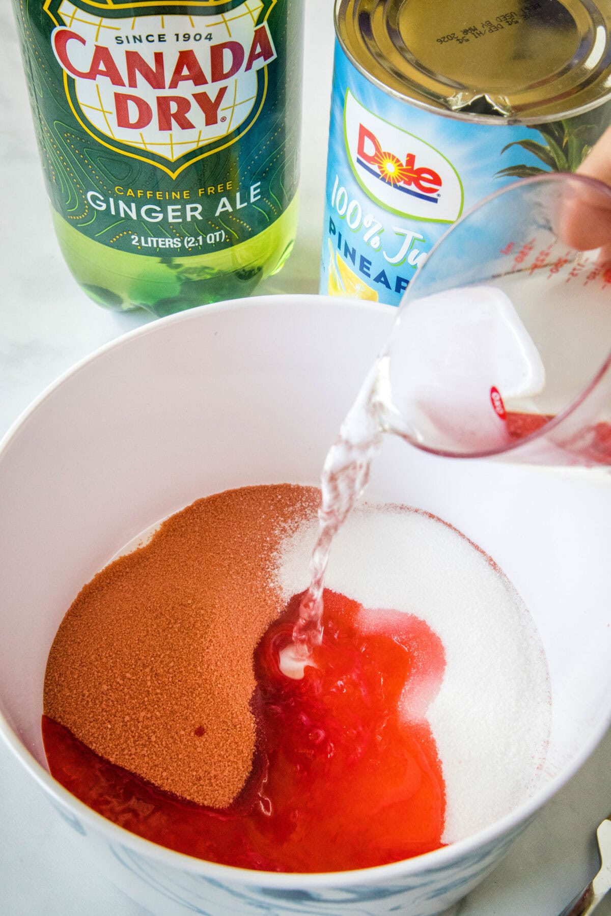 Water being poured into a bowl of cherry Jell-O.