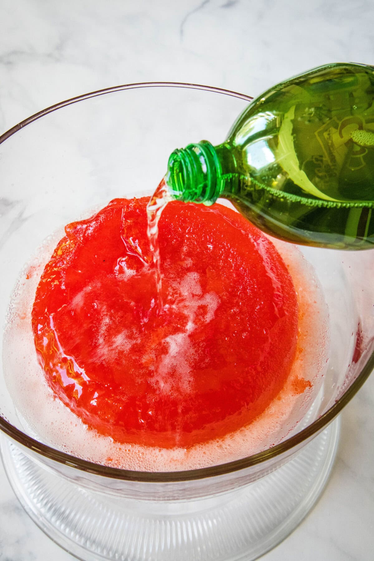 Ginger ale being poured into a large bowl of holiday punch.