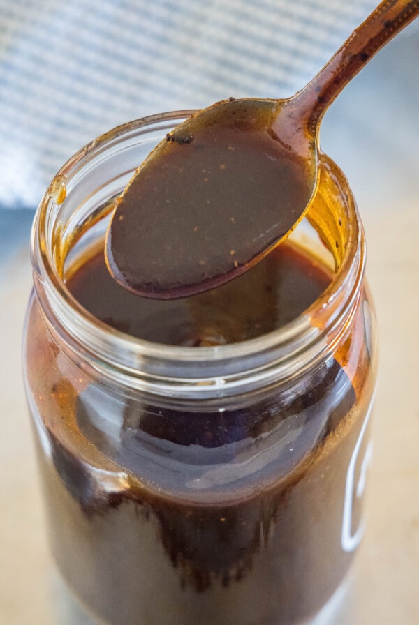 A spoonful of homemade barbecue sauce held over a mason jar.