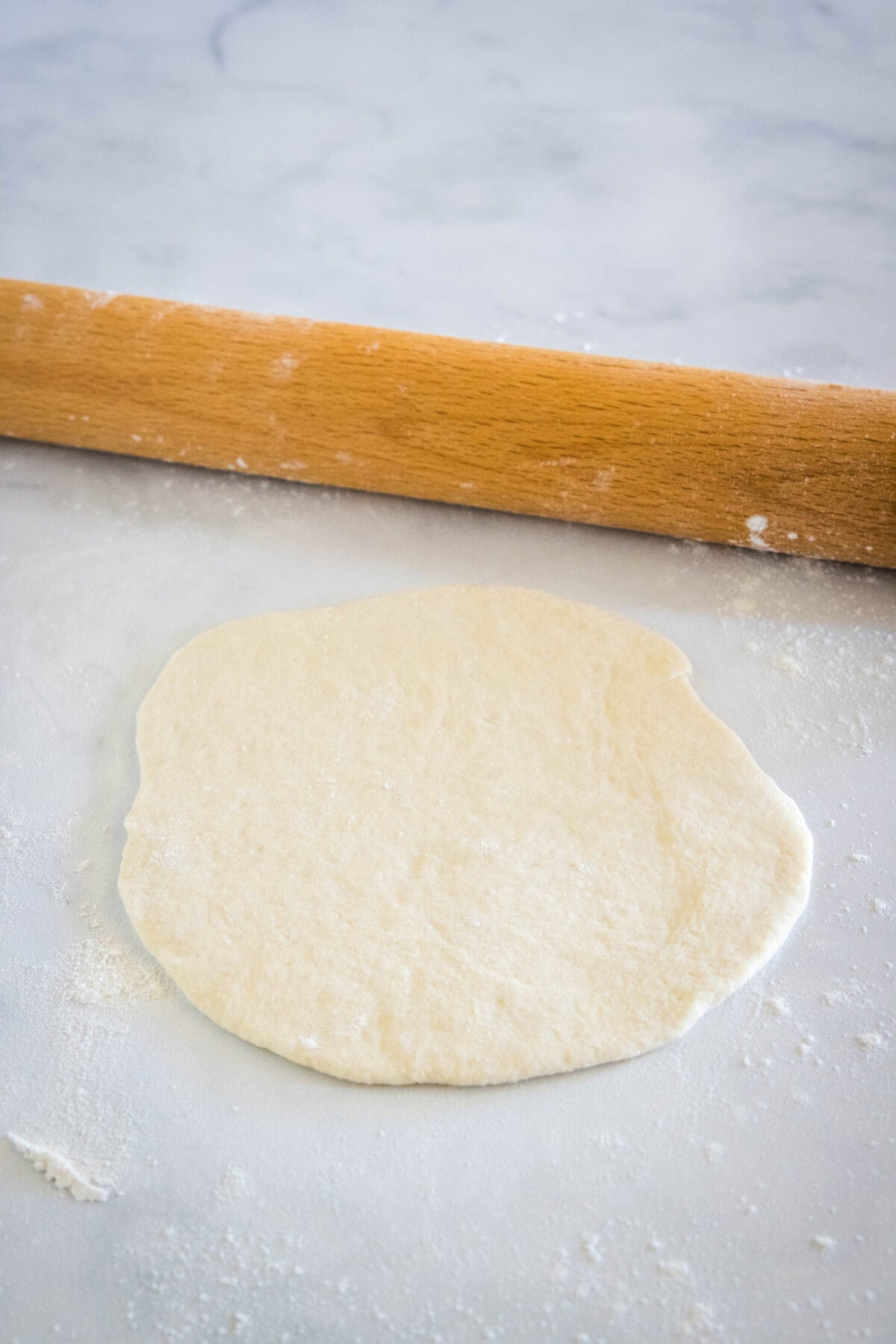 Pita bread dough rolled out into a flat circle.