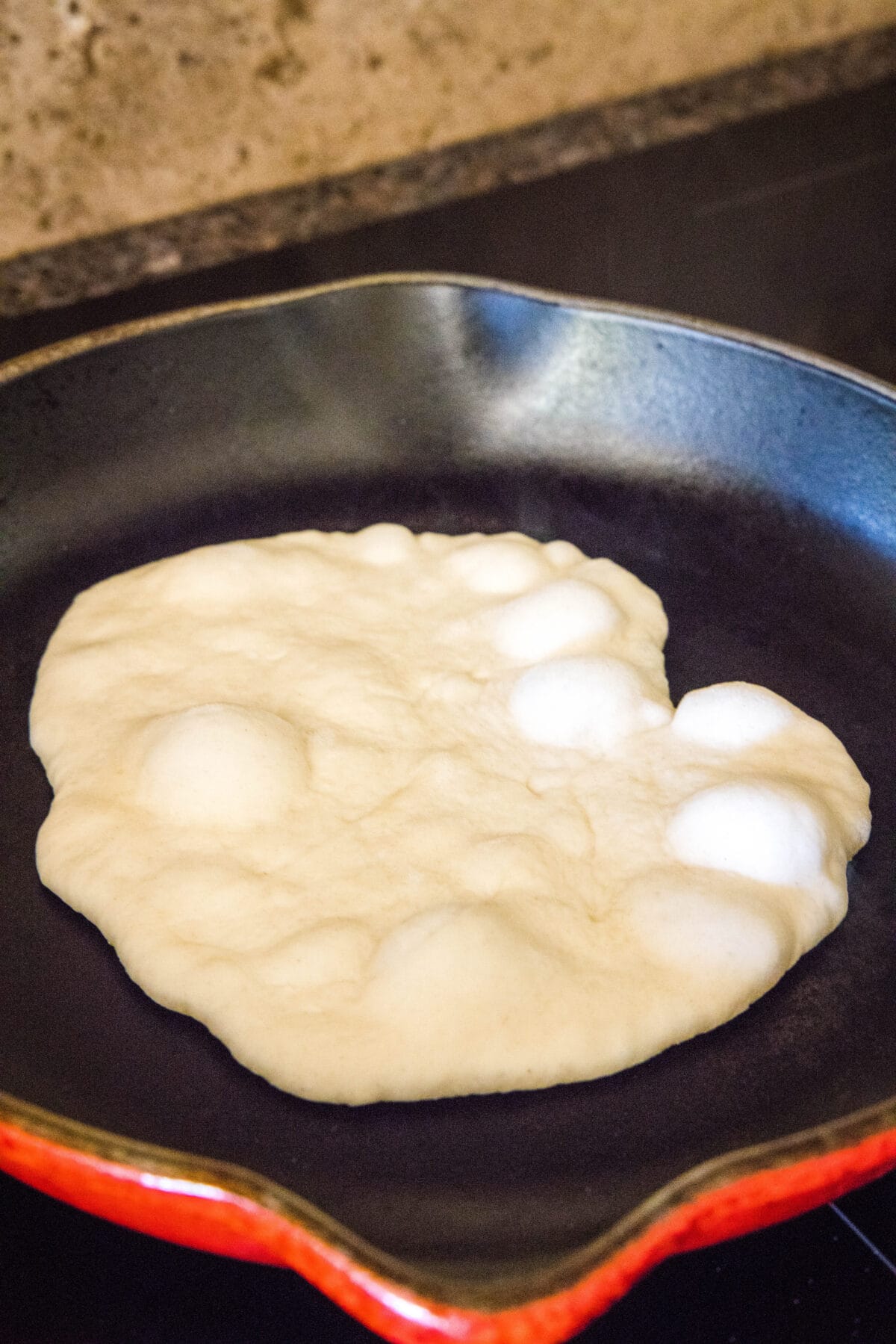 Pita bread dough puffing up on a hot skillet.