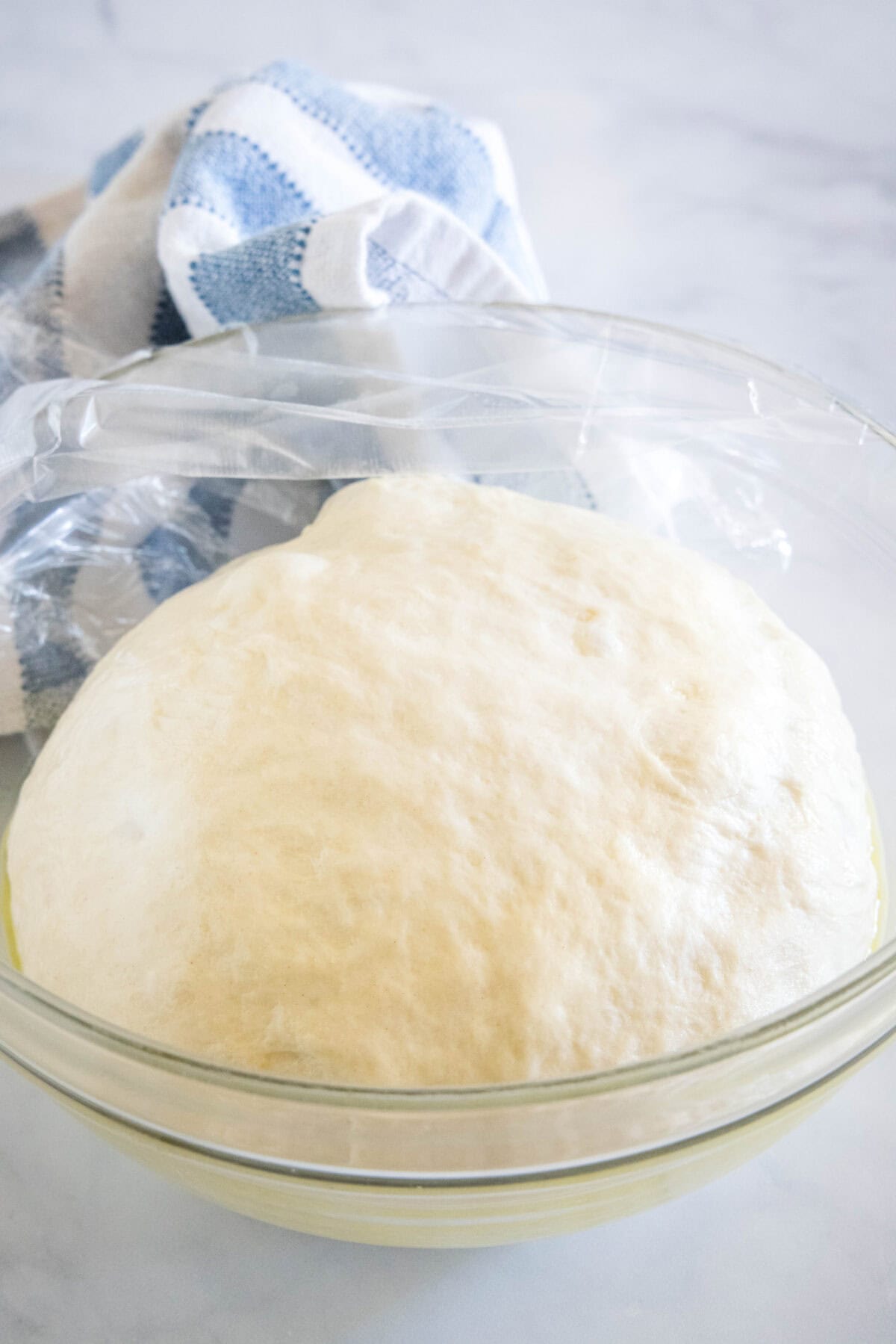 A ball of risen pita dough in a glass bowl.