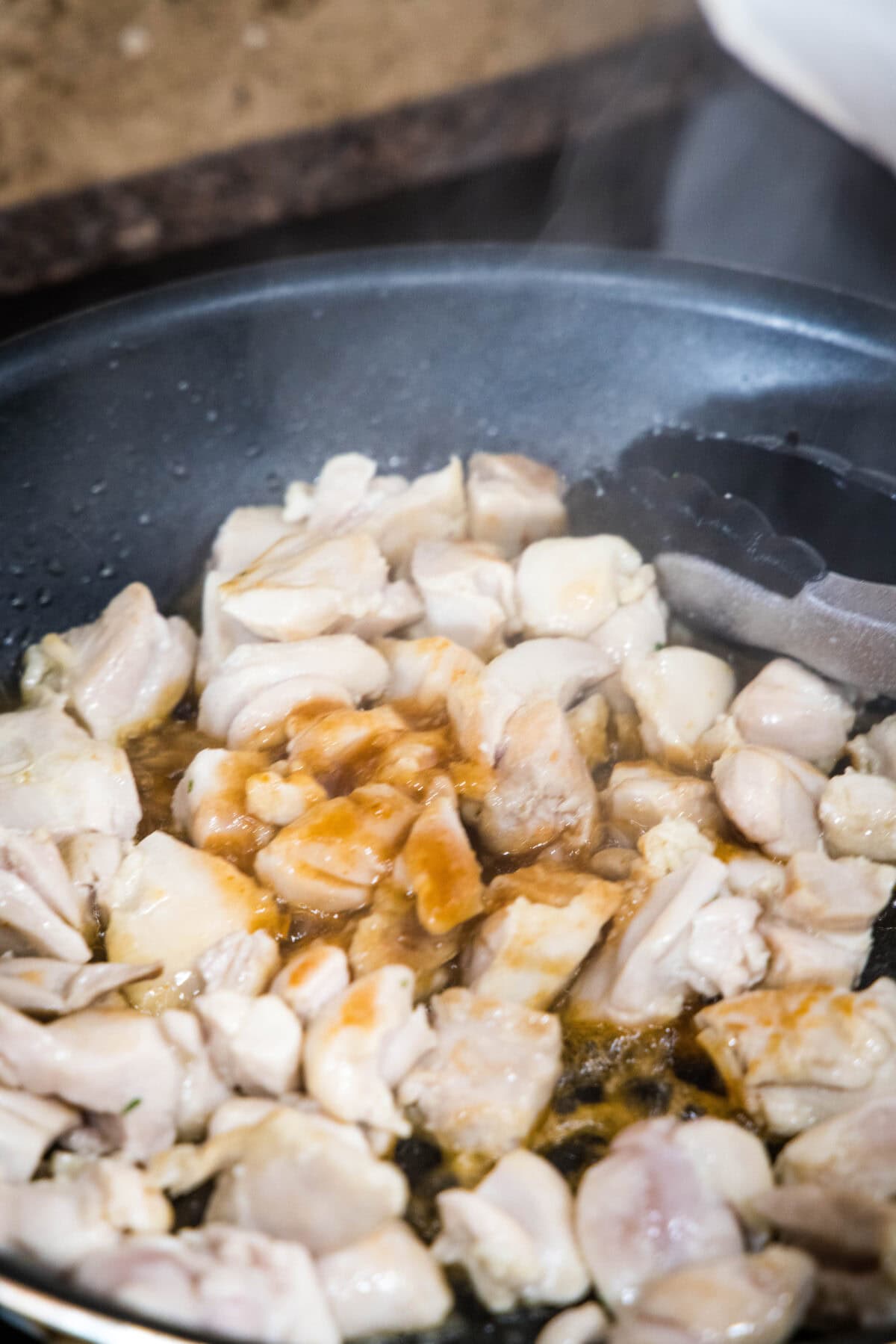 adding honey sriracha sauce to skillet with chicken
