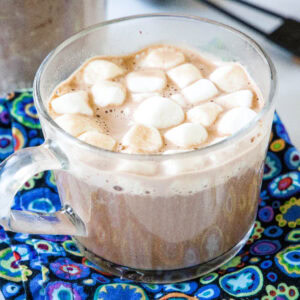 Hot chocolate in a clear mug topped with mini marshmallows.