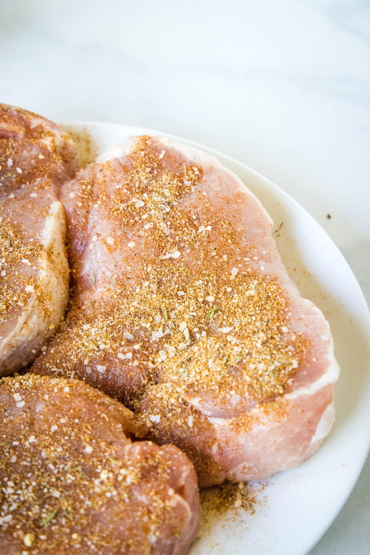 Seasoned pork chops on a white plate.