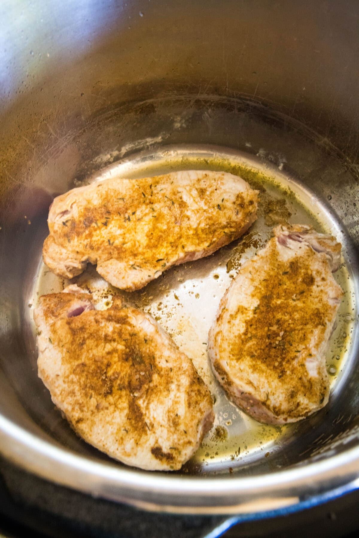 Seasoned pork chops searing inside the instant pot.