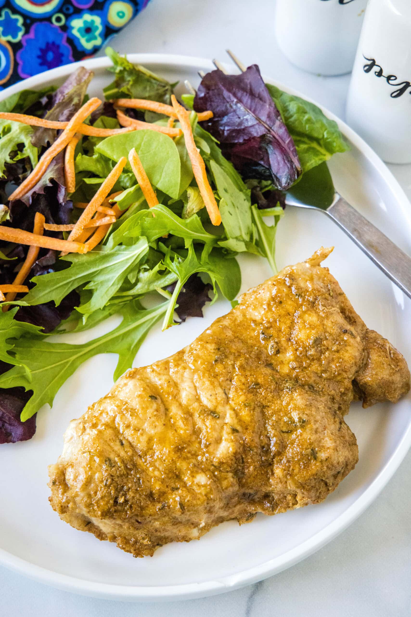 An instant pot pork chop with a side of salad on a white plate.