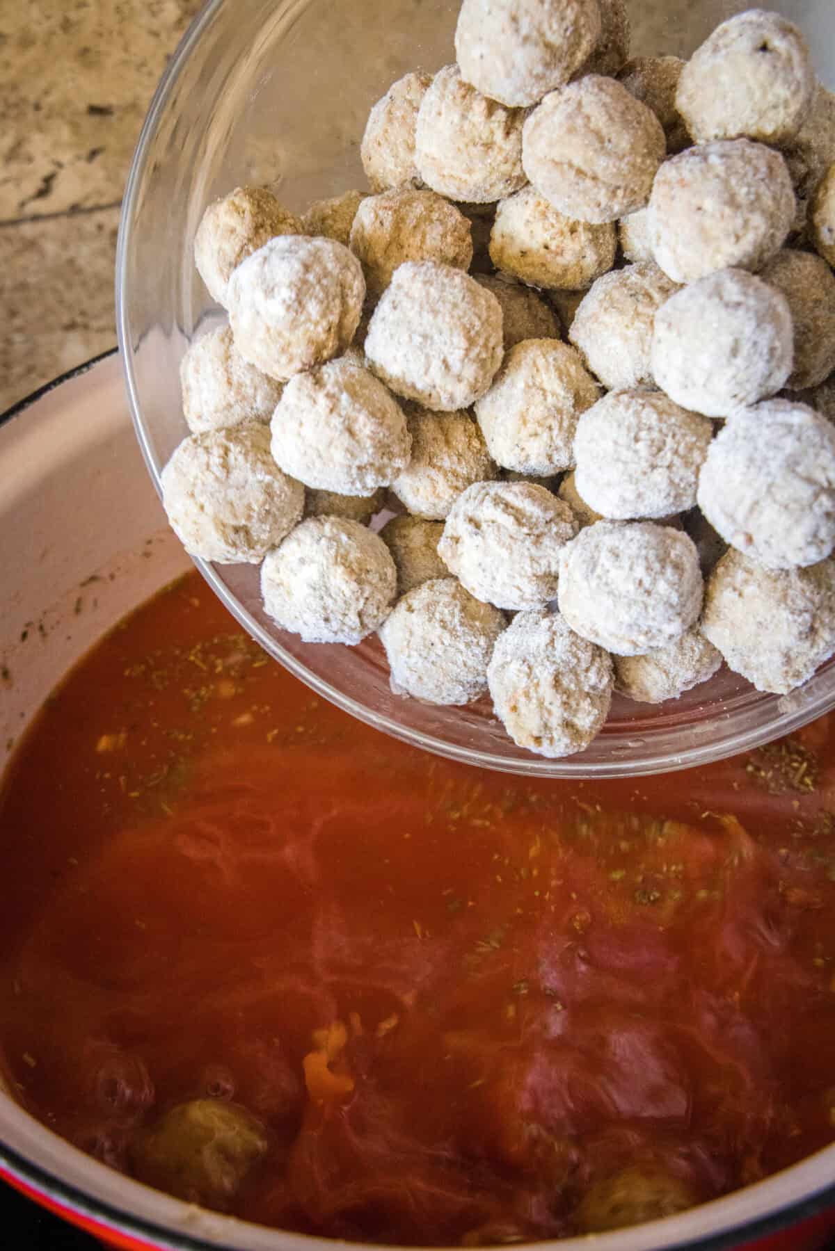 adding frozen meatballs to pot of soup