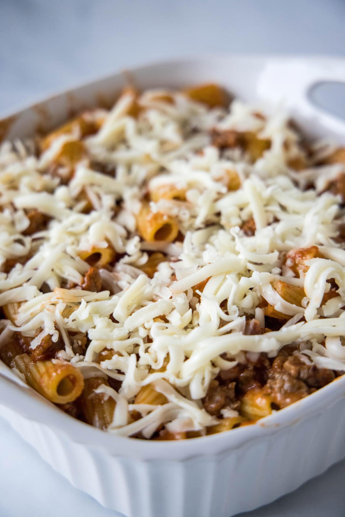 sausage casserole ready for the oven topped with shredded cheese