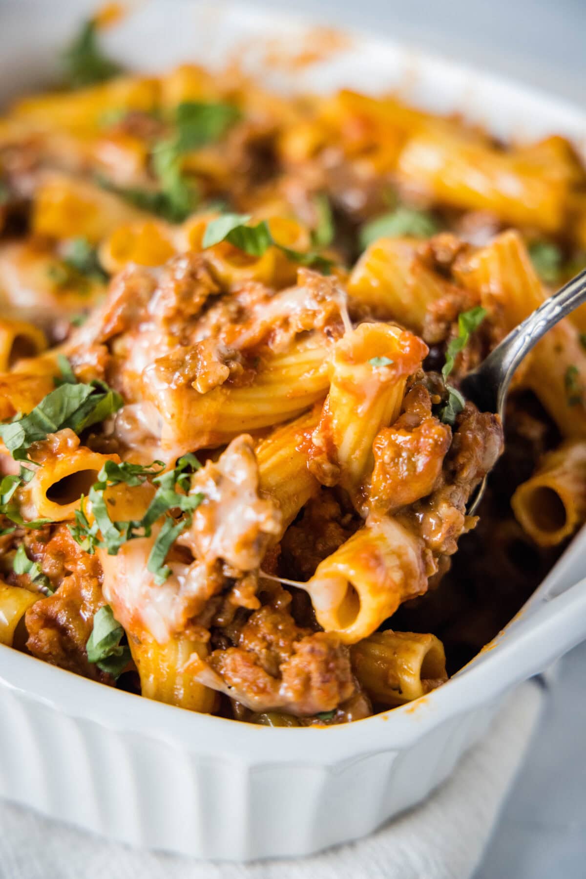scooping italian sausage casserole out of baking dish
