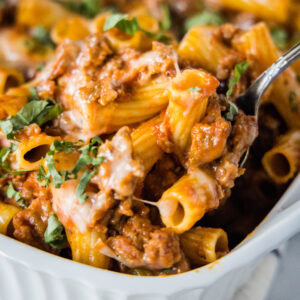 close up scooping sausage casserole out of baking dish