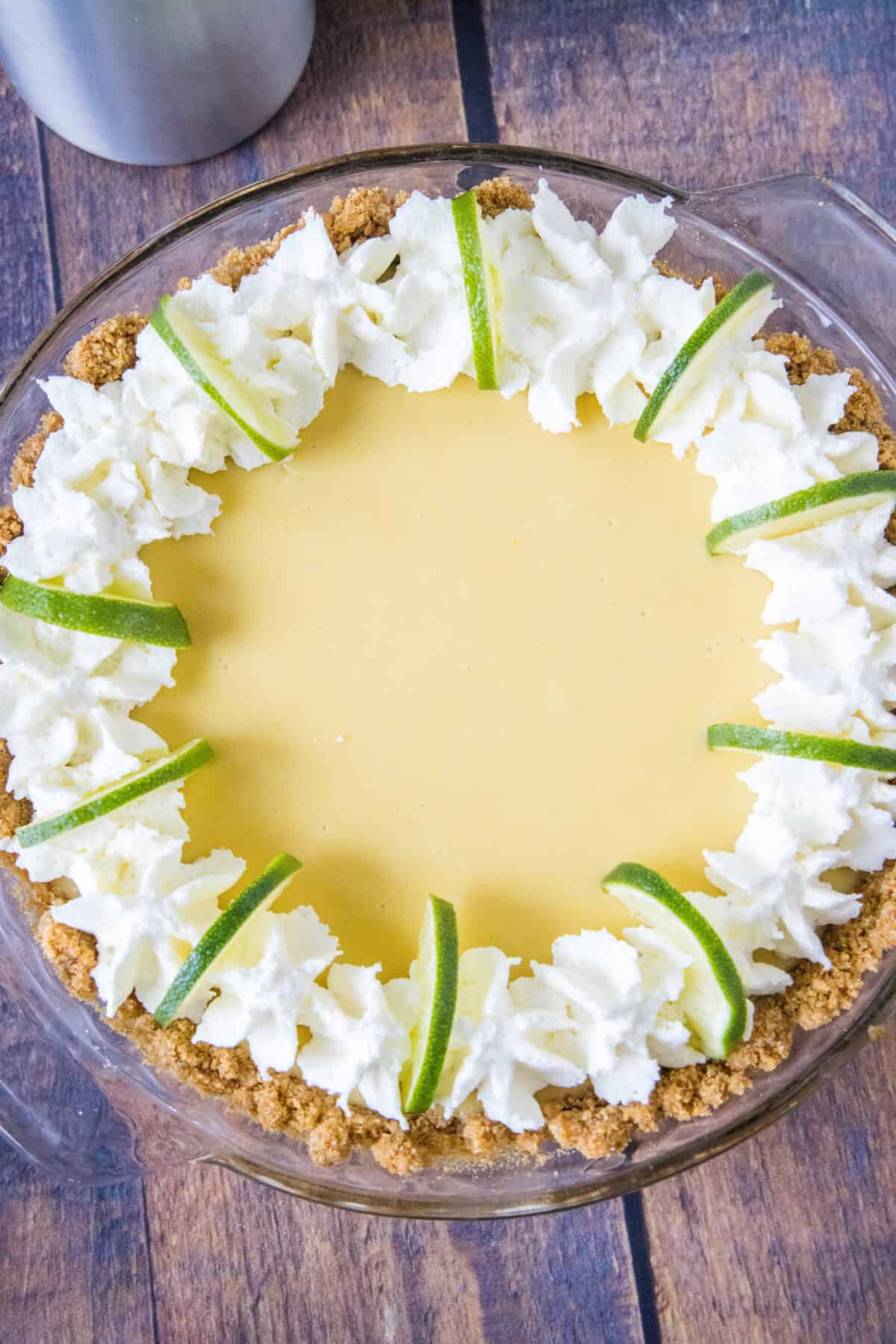 looking down on key lime pie with whipped cream and lime slices