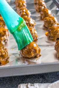 brushing sauce on meatballs