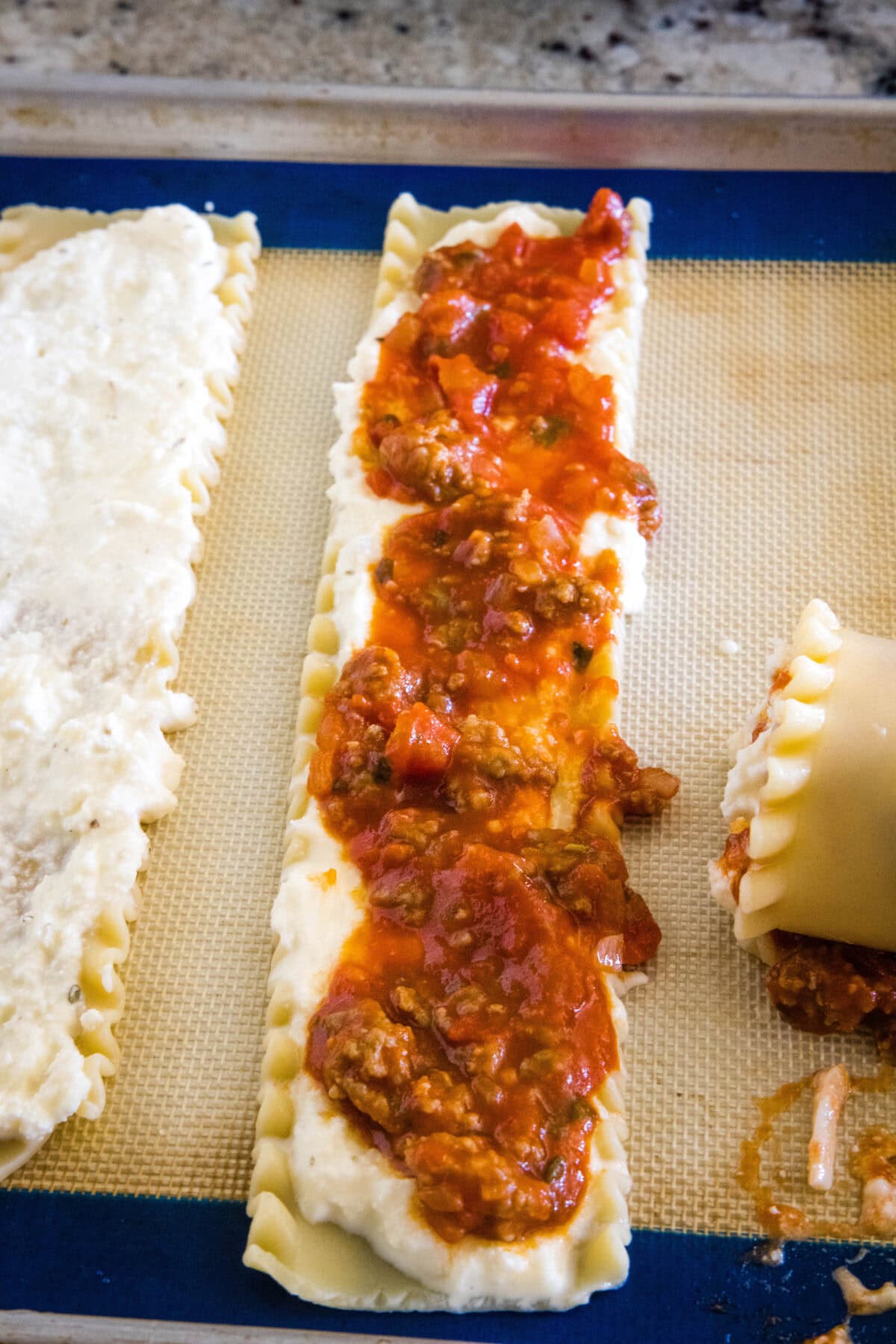 Sauce spread over a lasagna sheet on a baking pan.