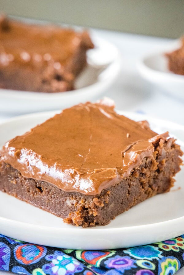 A lunch lady brownie on a white plate with more brownies on plates in the background.