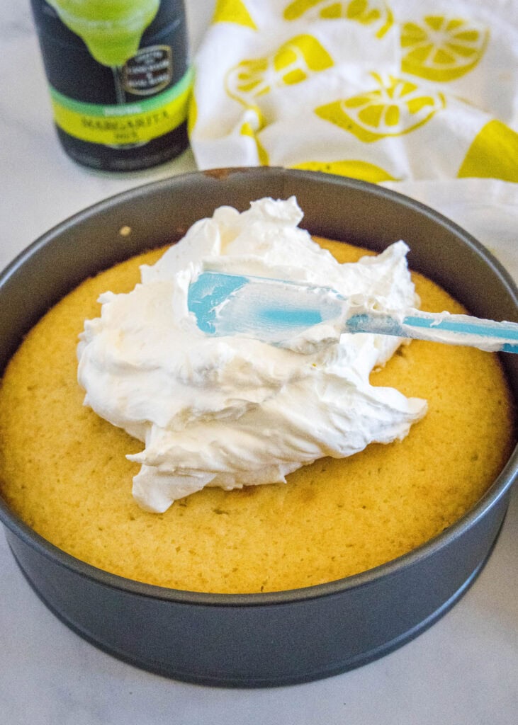 spreading whipped cream over baked cake