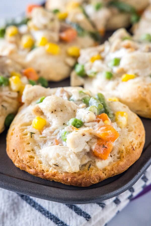 Close up of a mini chicken pot pie in a muffin tin with more mini pies in the background.