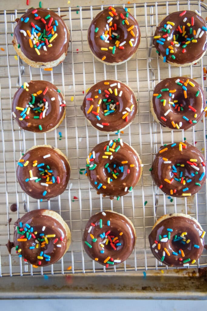 a dozen chocolate donuts on wire rack