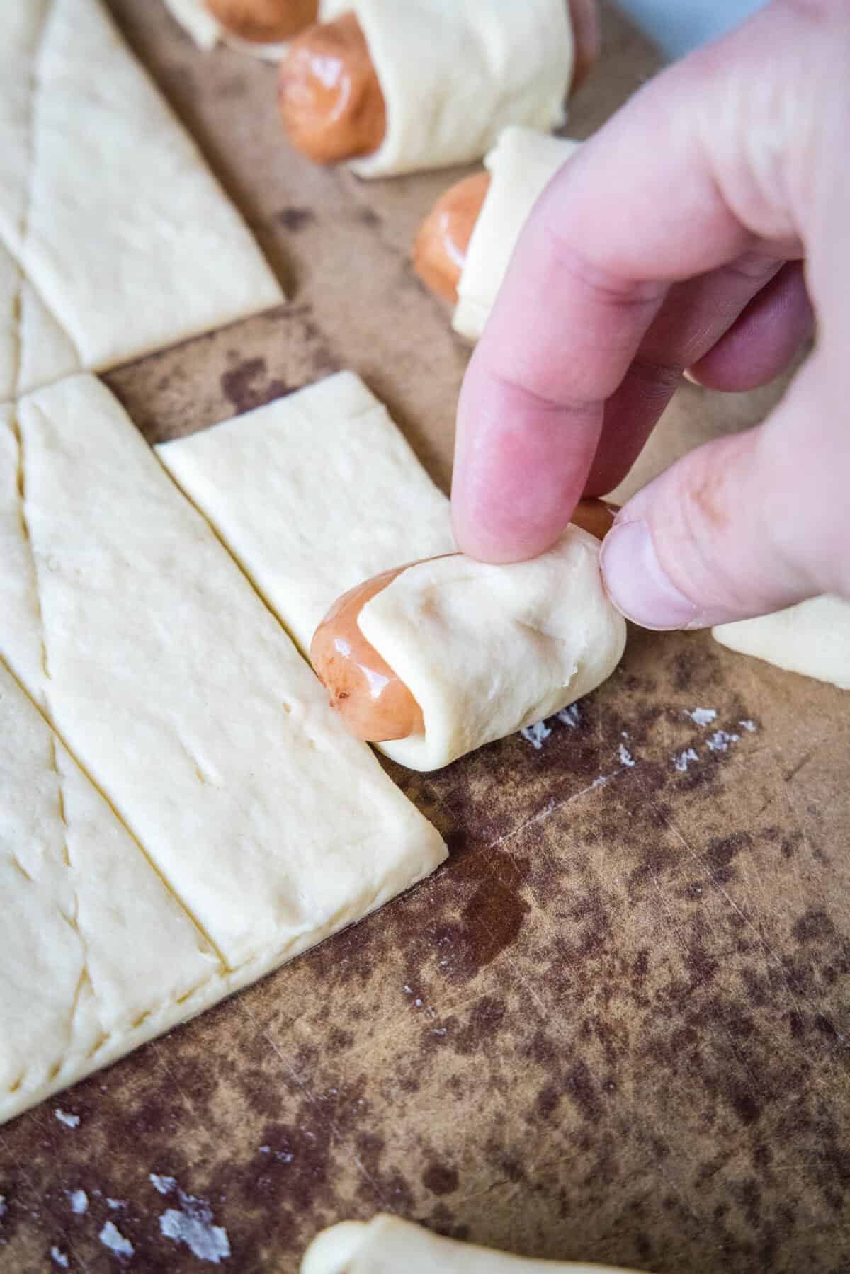 rolling a cocktail sausage in crescent dough