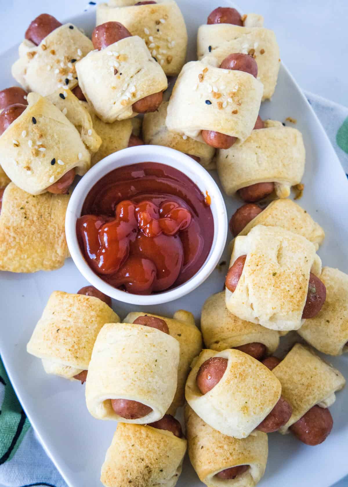 looking down on serving platter with mini pigs in a blanket with ketchup