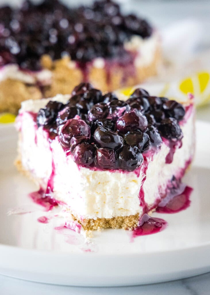 slice of no bake cheesecake on white plate with a bite missing