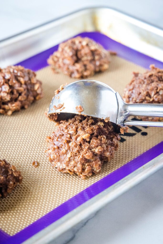 scooping no bake cookies onto a baking sheet