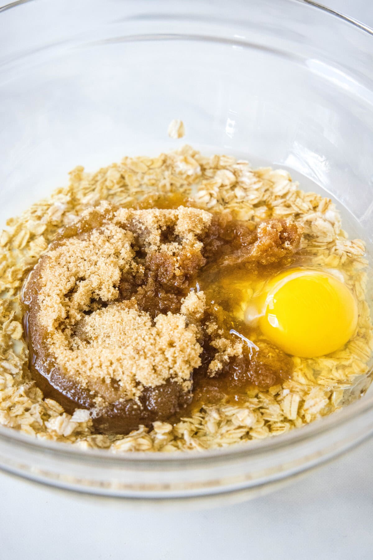 Eggs and wet ingredients combined with brown sugar in a glass bowl.