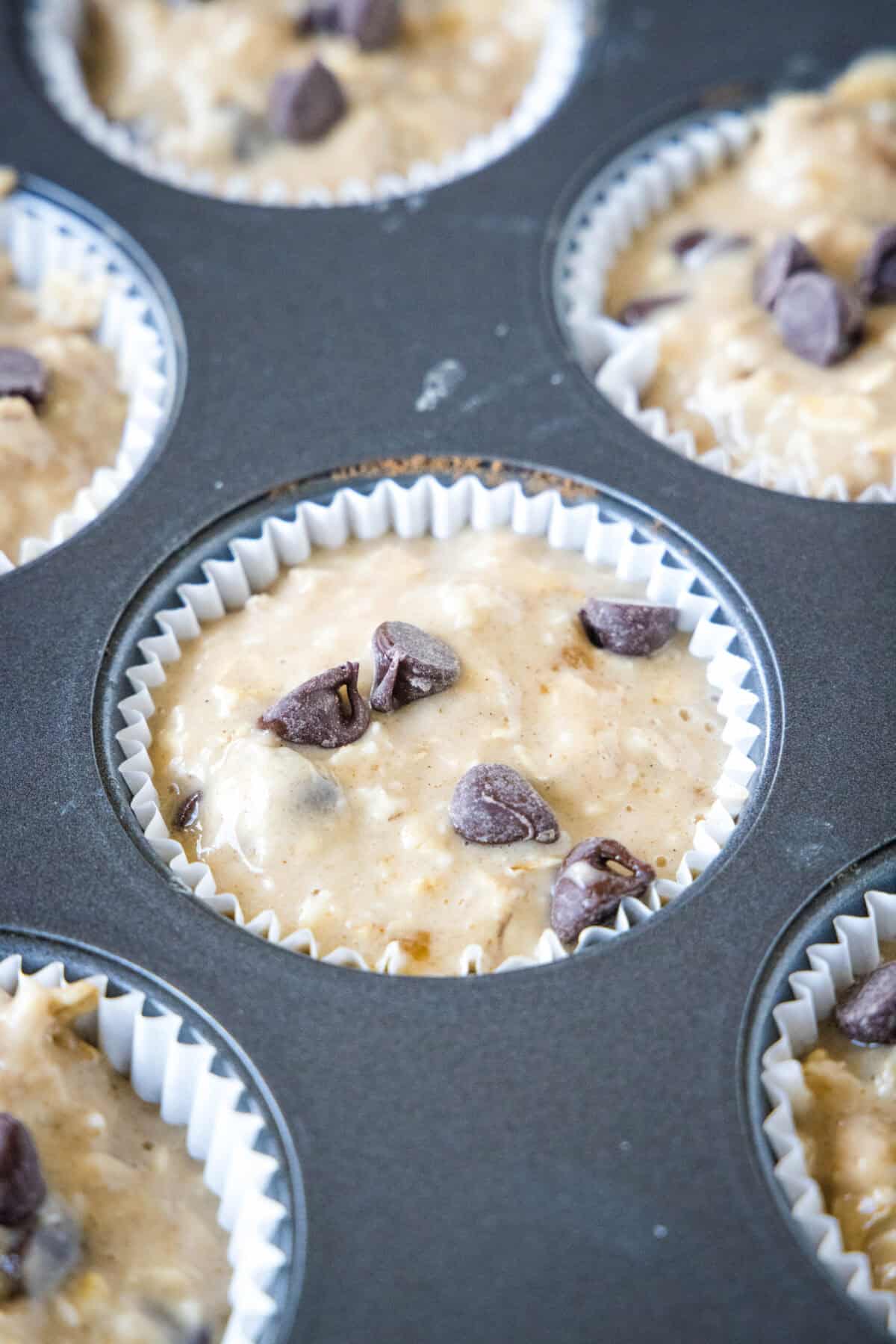 Close up of a lined muffin tin filled with oatmeal chocolate chip muffin batter.