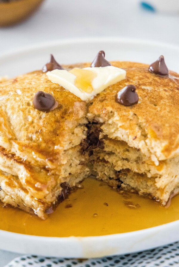 cropped close up pancakes with a bite missing on a white plate