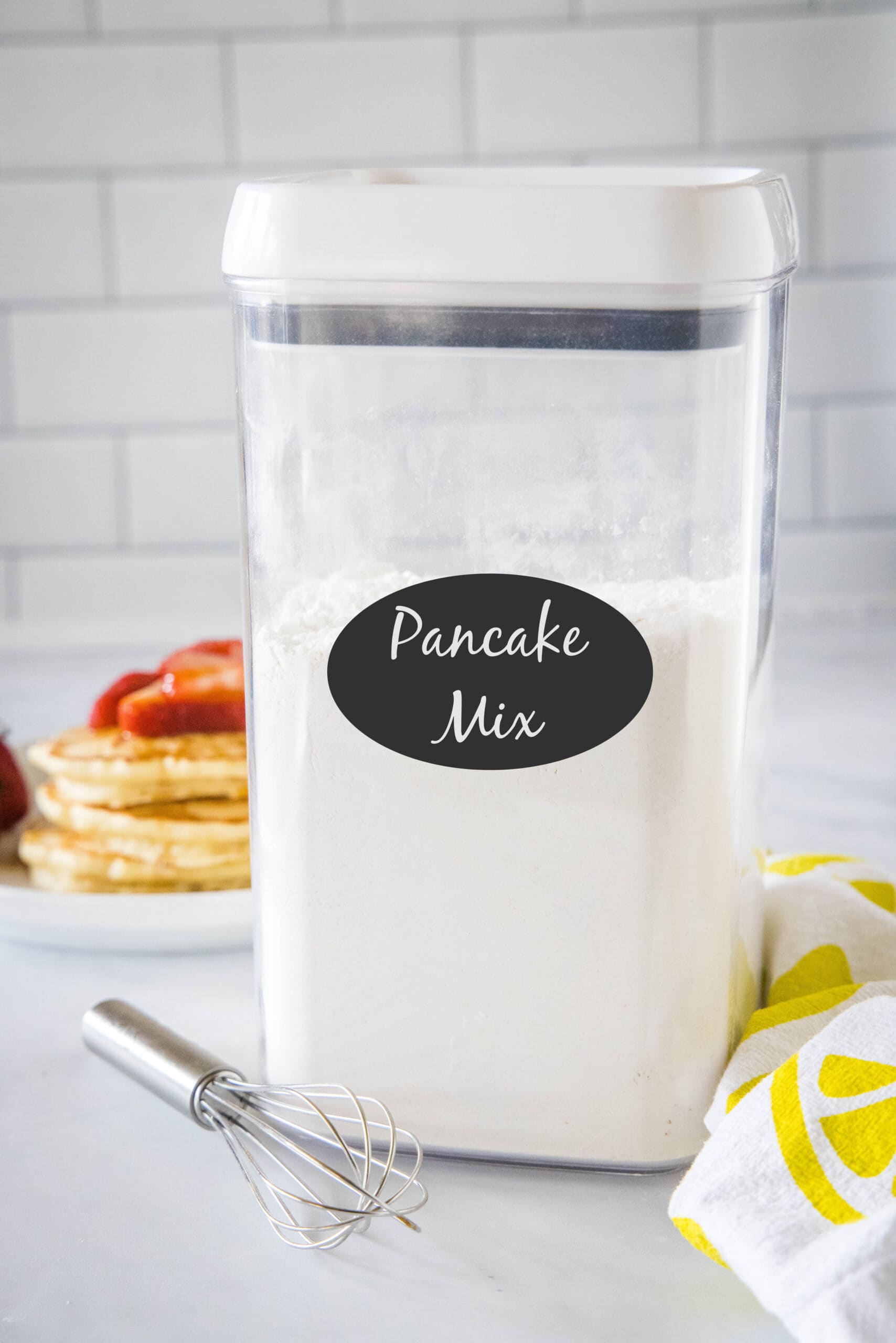 Homemade pancake mix in a labeled airtight container on a countertop.