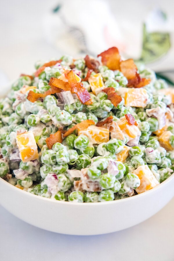 Pea salad in a white bowl.